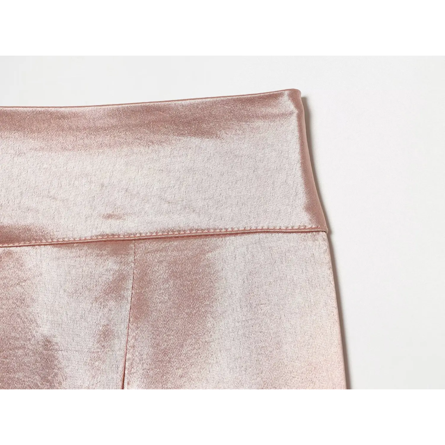 Close‑up back waistband stitching and textured satin fabric detail of blush trousers