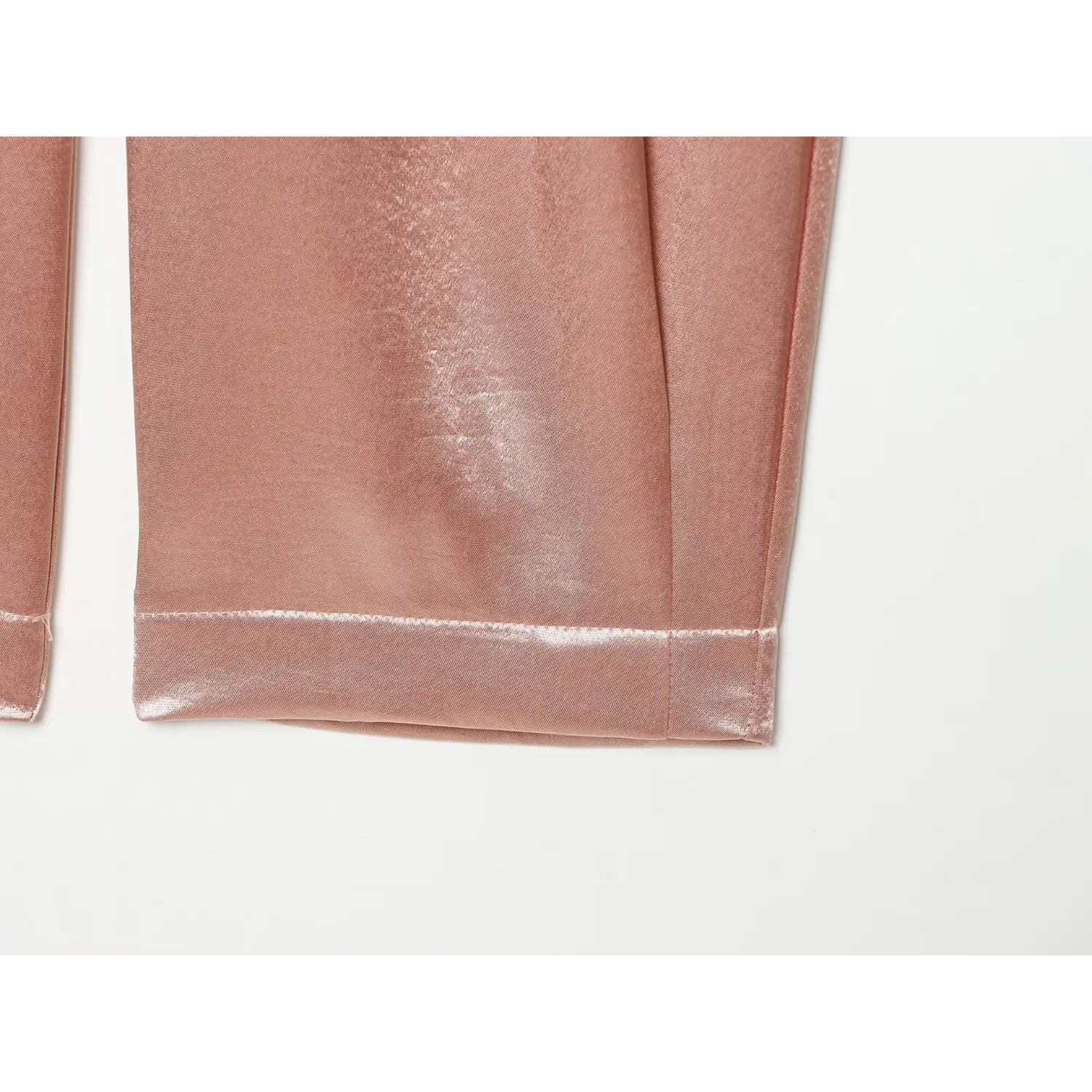 Close‑up cuffed hem stitching of blush pink textured satin tapered pants