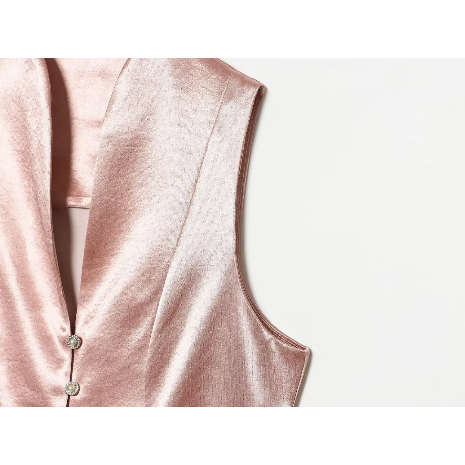 Close‑up shot armhole and shoulder seam detail of blush pink textured satin vest