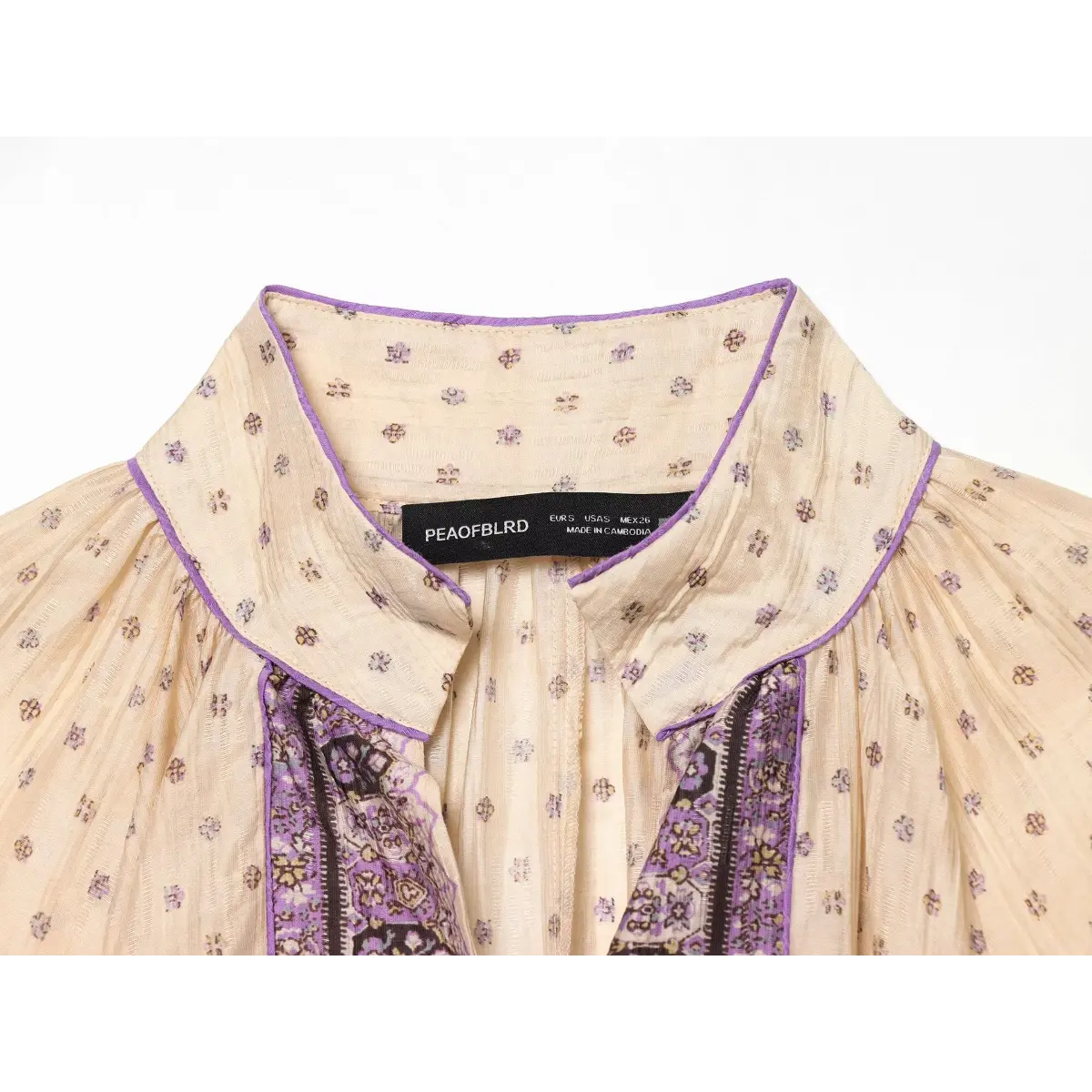 Close-up of the high collar, inner label, and V-neck opening on a boho printed mini dress.