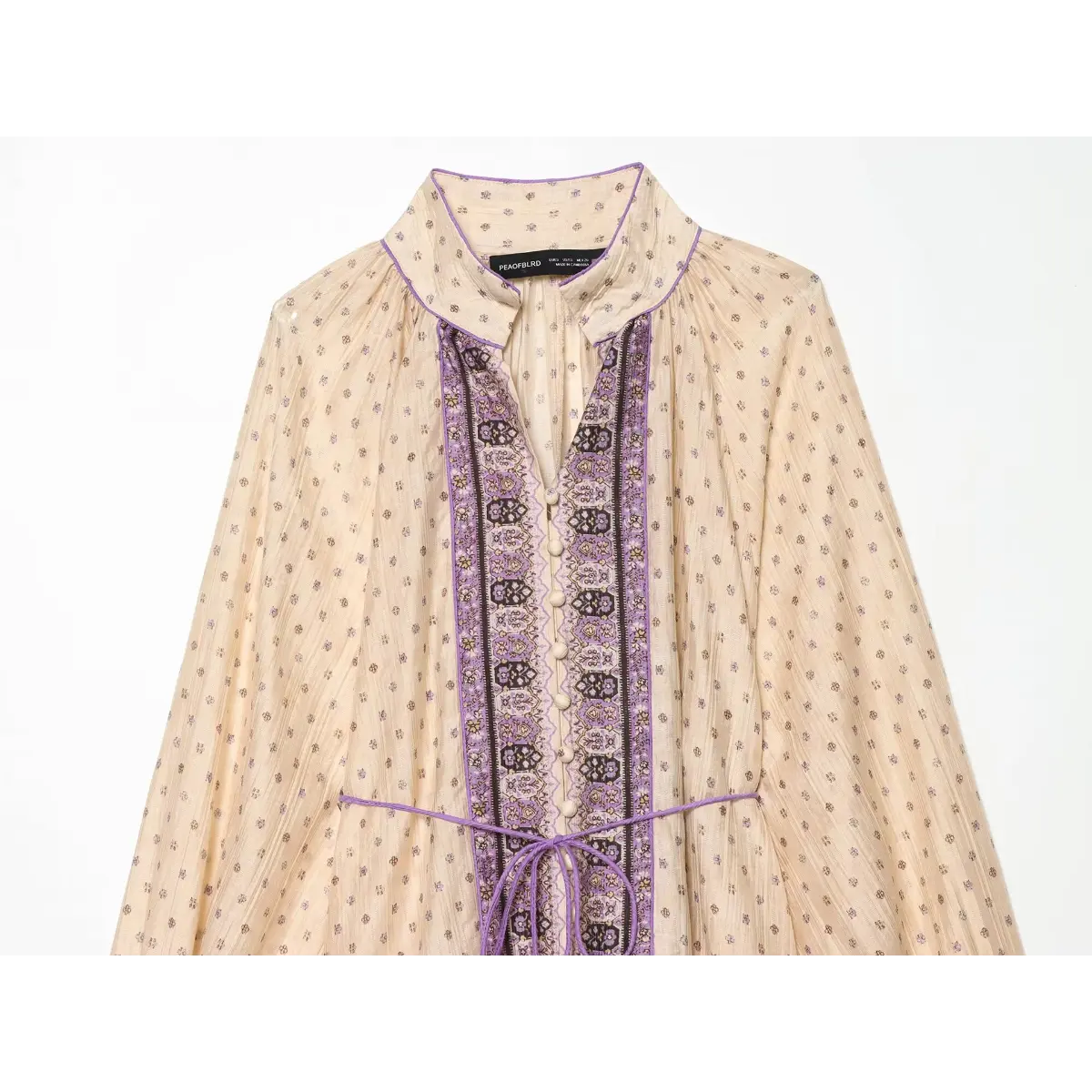 Front view of a boho printed mini dress, highlighting the V-neckline, decorative purple panel, and button placket.