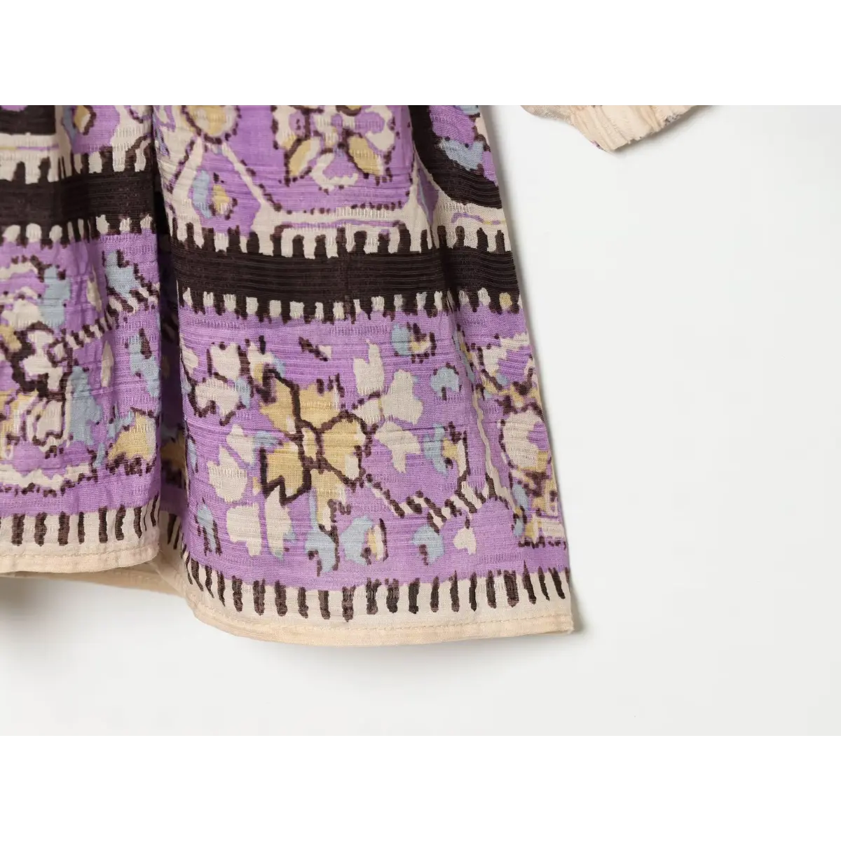 Close-up of the decorative purple and black border on the hem of a boho printed mini dress.