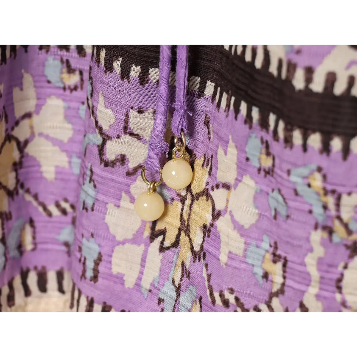 Close-up of the purple waist tie with gold bead accents on a boho printed mini dress.