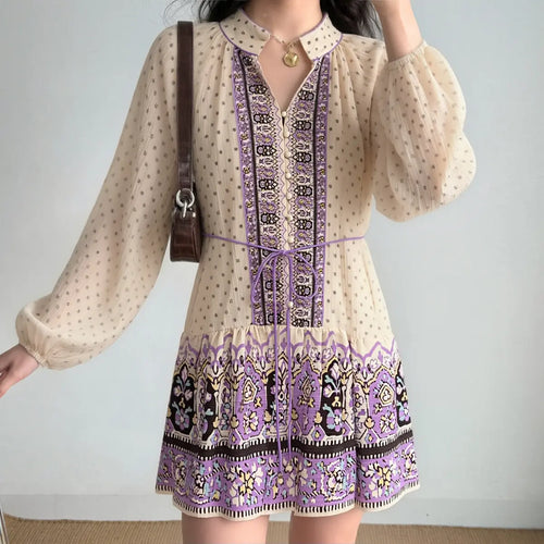 Woman styled in a boho printed mini dress with balloon sleeves, decorative front panel, and gathered hem, accessorized with a brown shoulder bag.