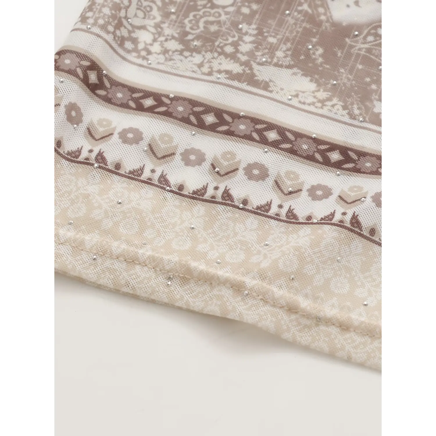 Macro hem texture shot sheer stretch mesh, border vintage floral paisley bandana print, evenly distributed tiny silver hot fix rhinestones, finished woven trim edge