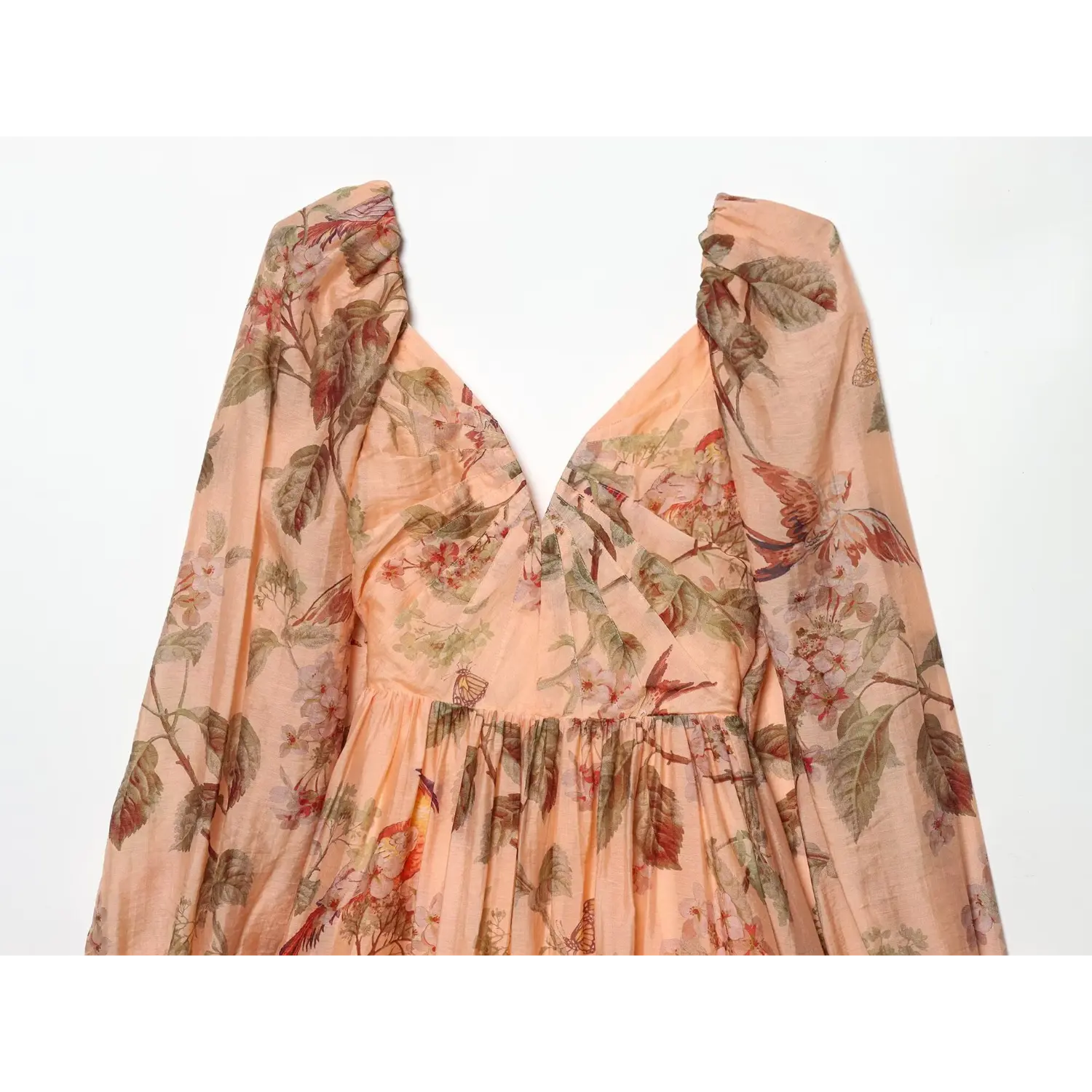 Close‑up of deep v neckline, ruched bust detail, vintage bird‑and‑floral print on peach lightweight fabric