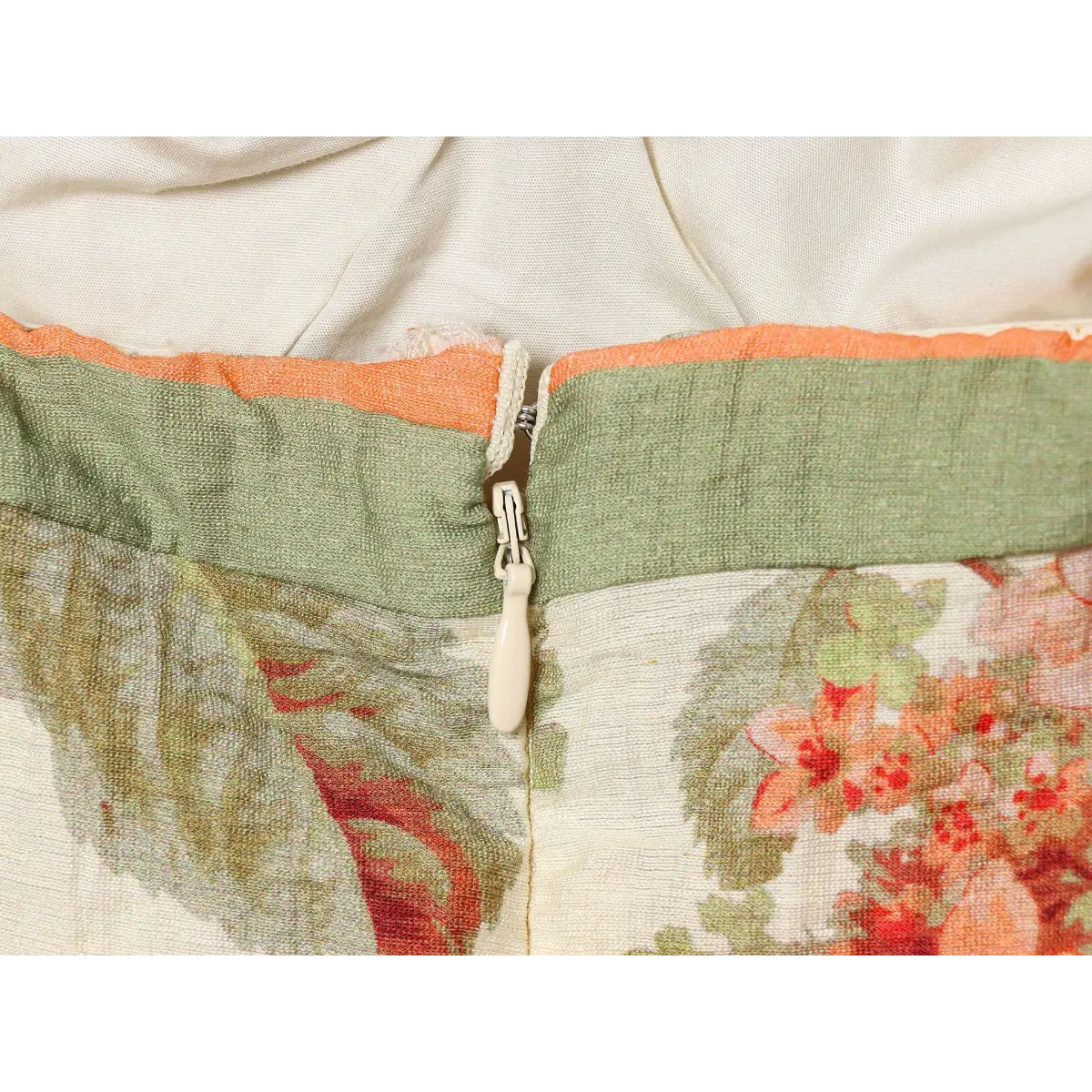 Center back hidden cream plastic zipper detail, finished green piped neck seam on linen blend floral tube dress.