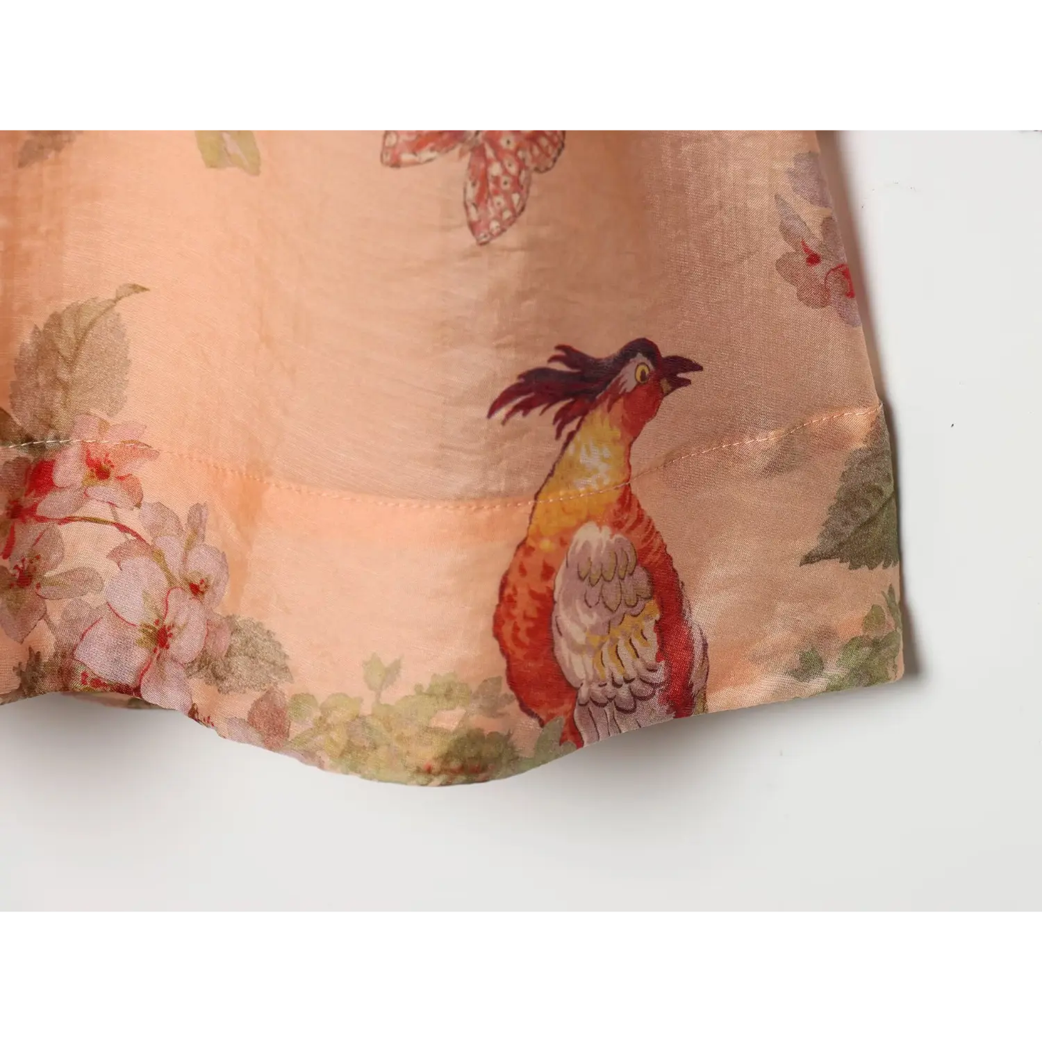 Close‑up of dress hem finished seam, vintage pheasant bird floral print on peach base fabric