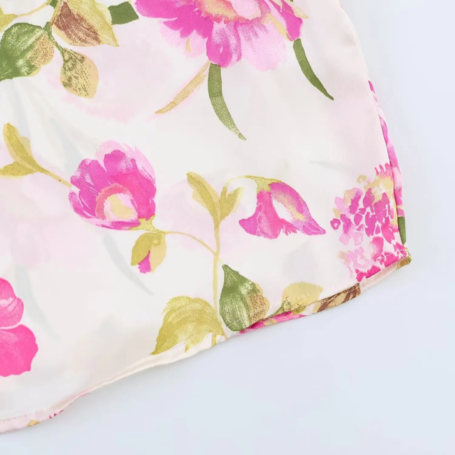 Curved bottom hem close-up, glossy satin texture, mixed peony and small flower print