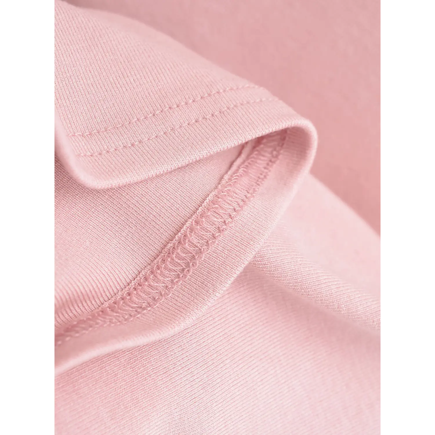 Extreme close-up of neat overlock hem stitching on dusty pink stretch ribbed cami tank fabric