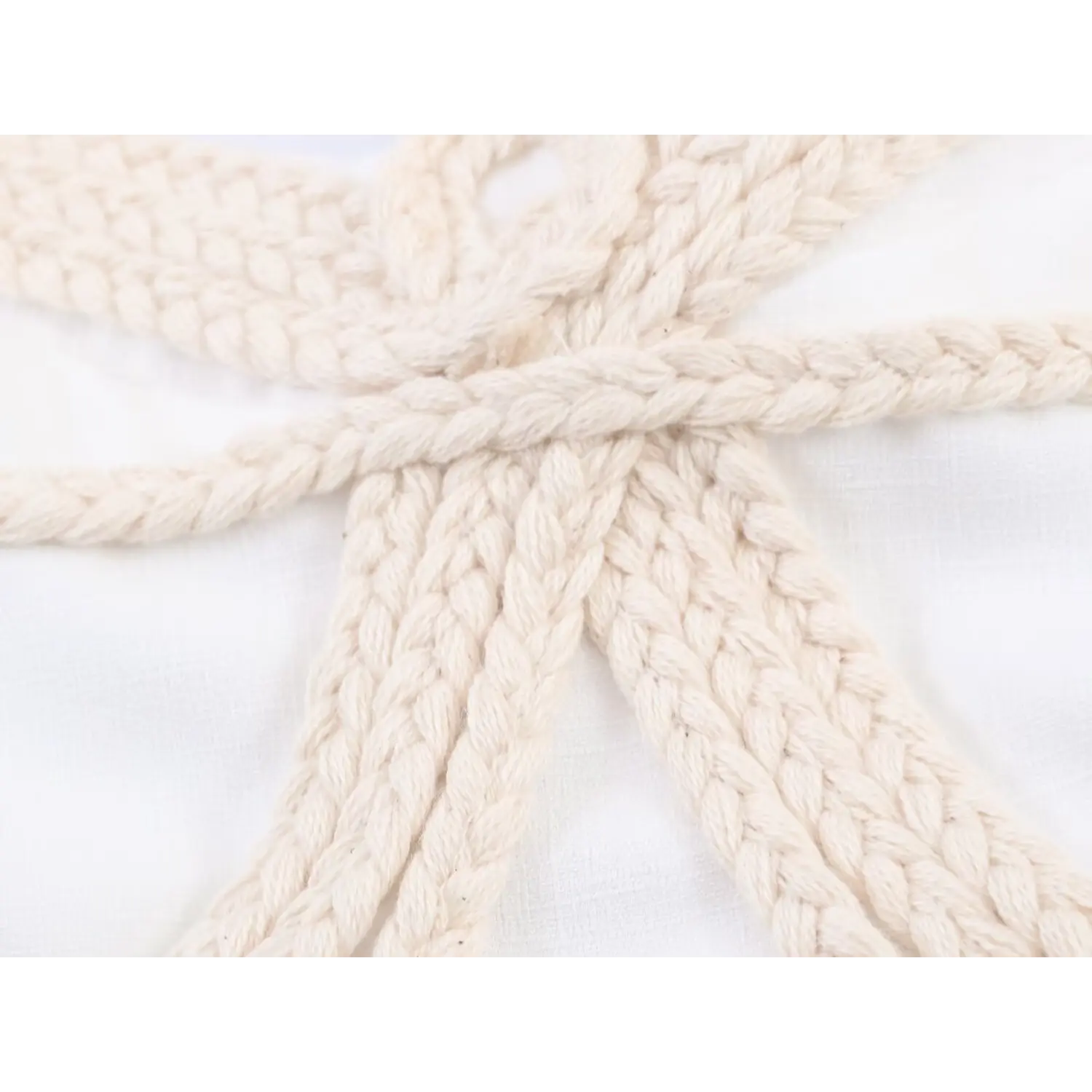Extreme close-up showing texture of beige braided rope butterfly decoration on camisole