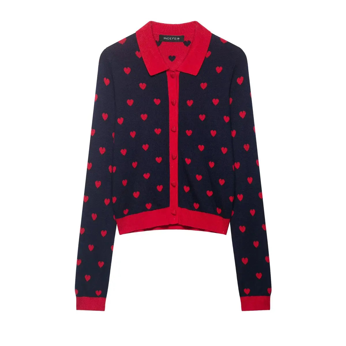  Close-up of the brand label and red collar on a navy and red heart-patterned knit cardigan.