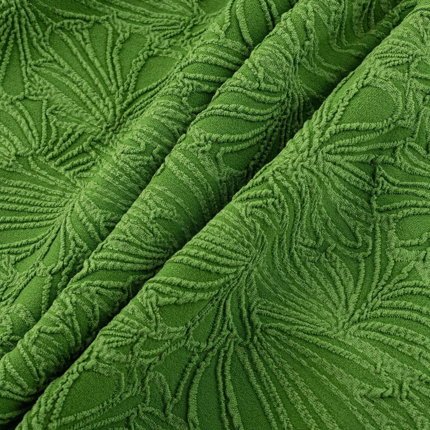 Flat lay close texture shot of vivid green stretch knit fabric, raised 3D ginkgo leaf embossed jacquard pattern with soft draped folded layers