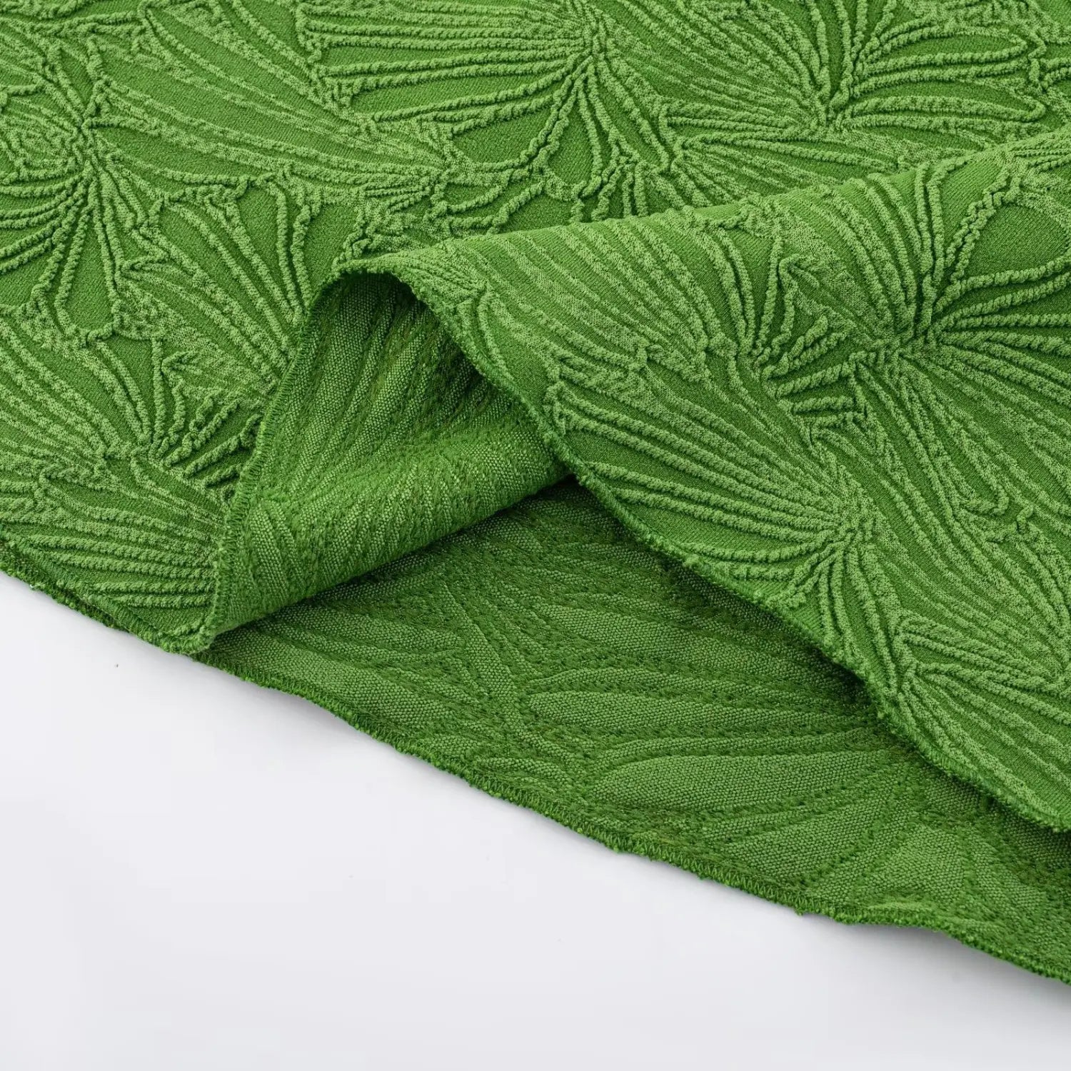 Partial flat shot showing reverse side of green stretch jacquard fabric, soft solid knit lining and neat finished raw hem stitching