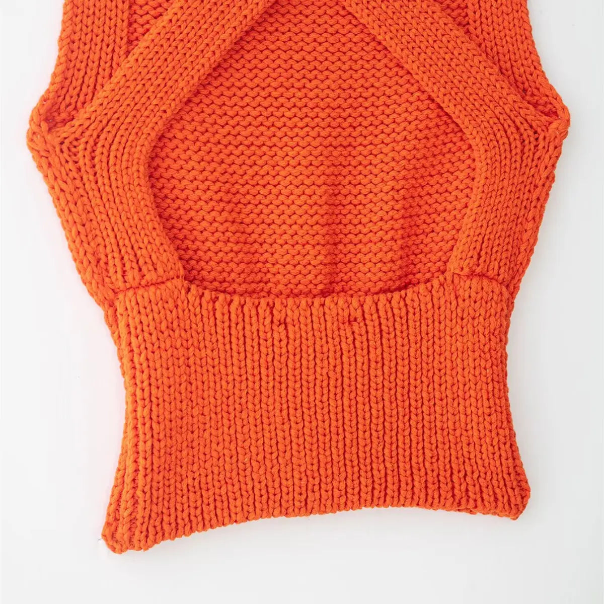 Front view of the bright orange knit cami, showing the crisscross wrap bust, ribbed waistband, and chunky knit texture