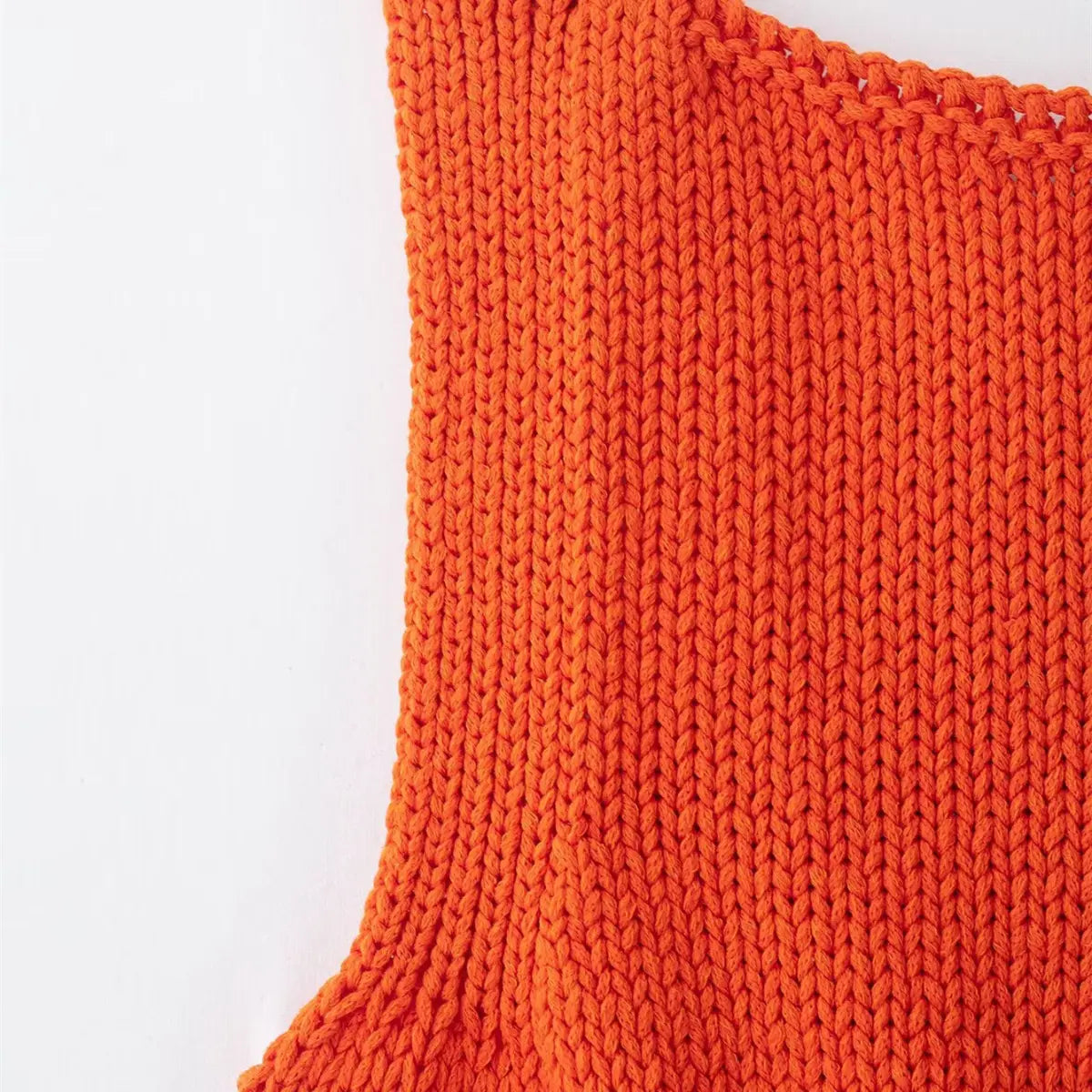 Side view of the bright orange knit cami, showing the sleeveless armhole and consistent vertical ribbing