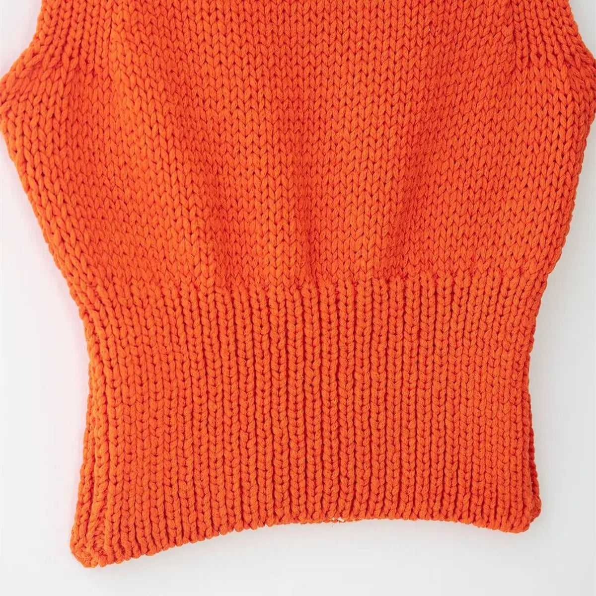 Close-up of the ribbed waistband on the bright orange knit cami, showing the tight knit texture and fitted silhouette