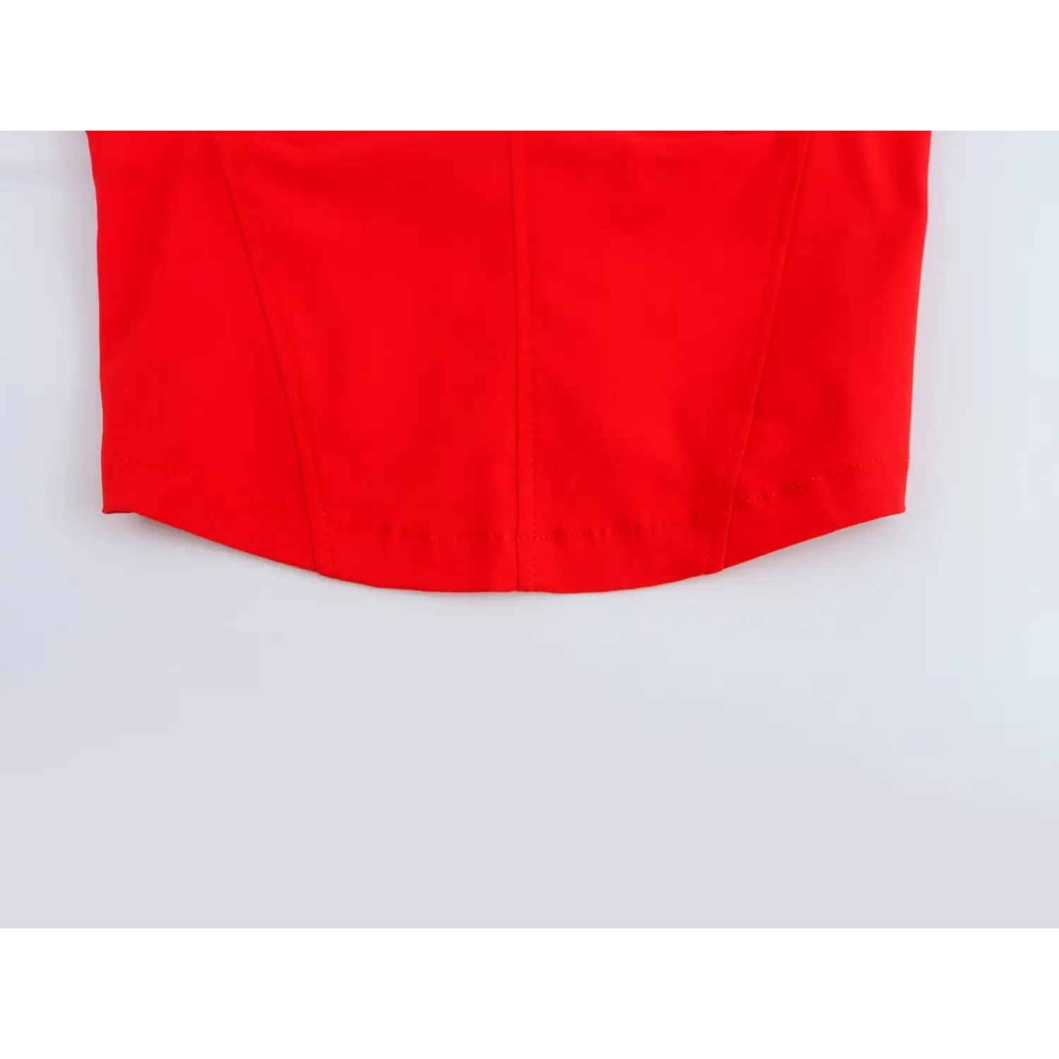Close-up of structured seam stitching at bottom hem on bright red corset crop top
