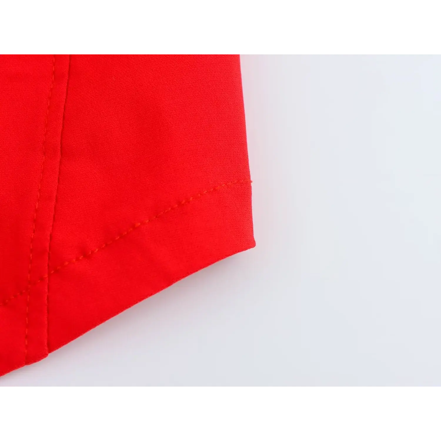 Close-up of bottom hem stitching and smooth fabric texture on bright red corset top