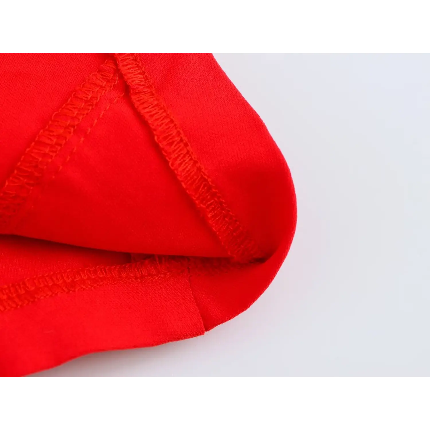 Close-up of inner overlocked stitching at bottom hem on bright red corset crop top