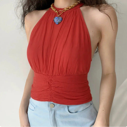 Front lifestyle shot on model, bright red draped halter cropped tank top, bust gathering, ruched waist, matched with light blue denim and thick chain necklace, chic casual summer outfit
