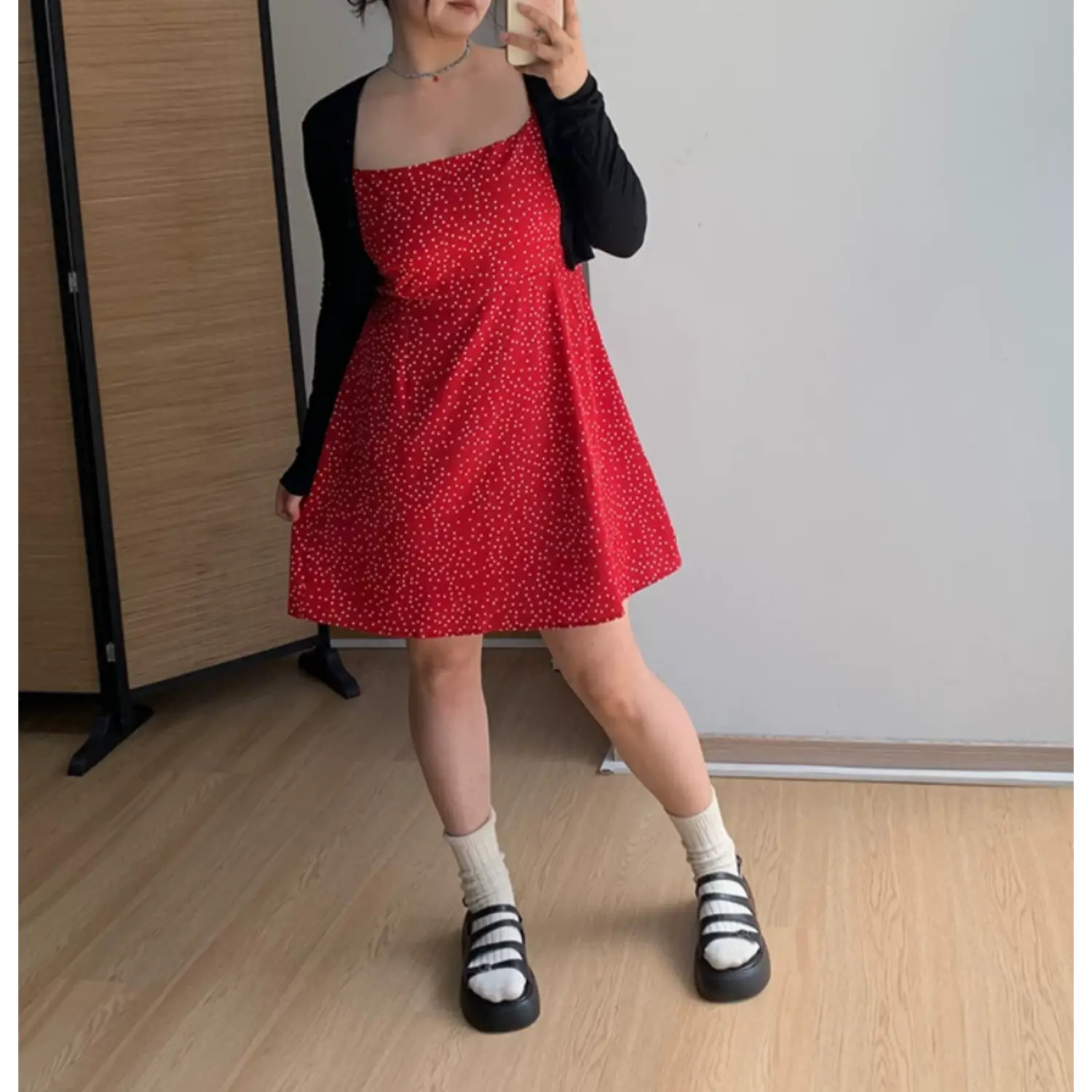 Full body indoor mirror shot of red white polka dot mini slip dress, layered slim black long sleeve cropped knit cardigan, white crew socks and black chunky multi-strap platform sandals