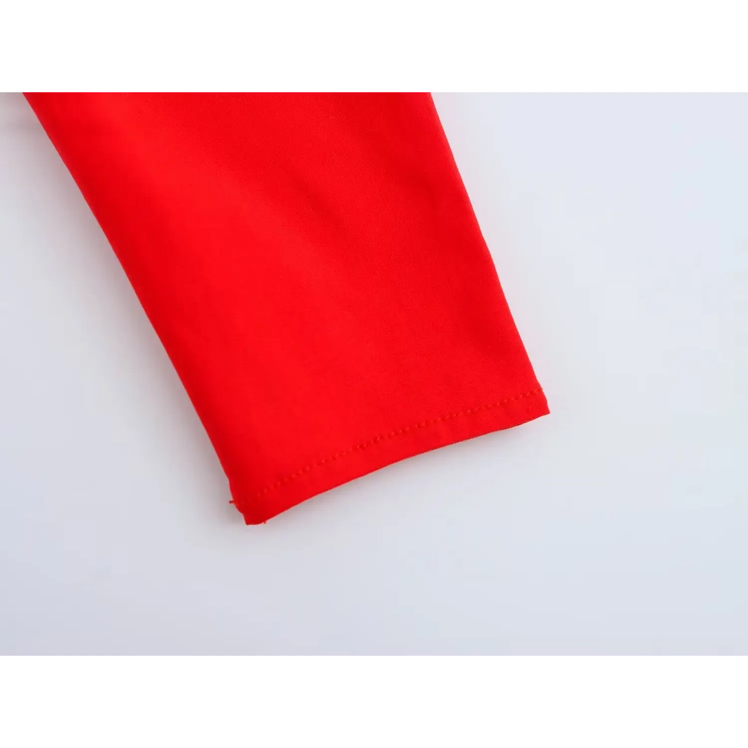 Close-up of sleeve cuff stitching detail on bright red puff sleeve corset top