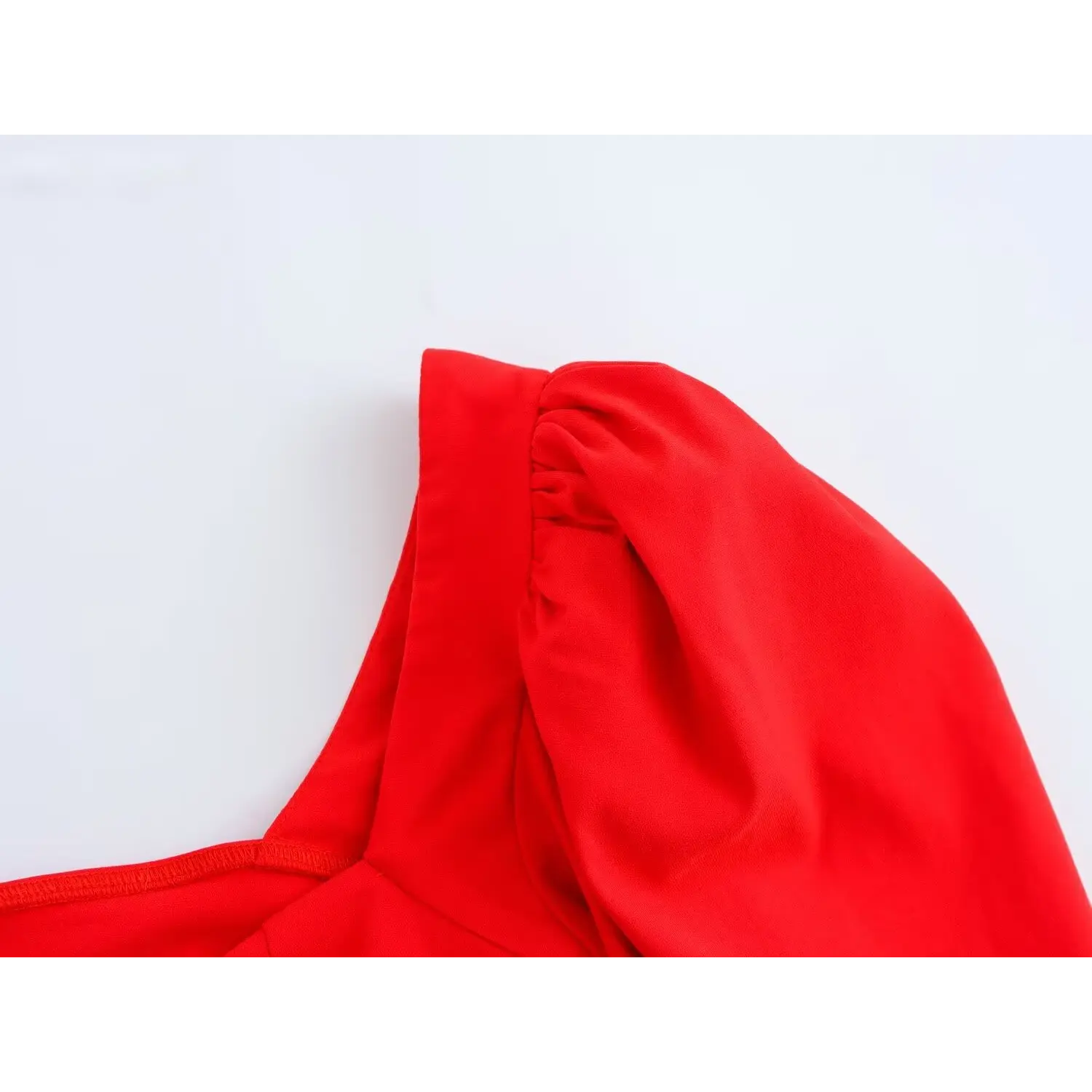 Close-up of puff sleeve gathering detail on bright red square neck corset top