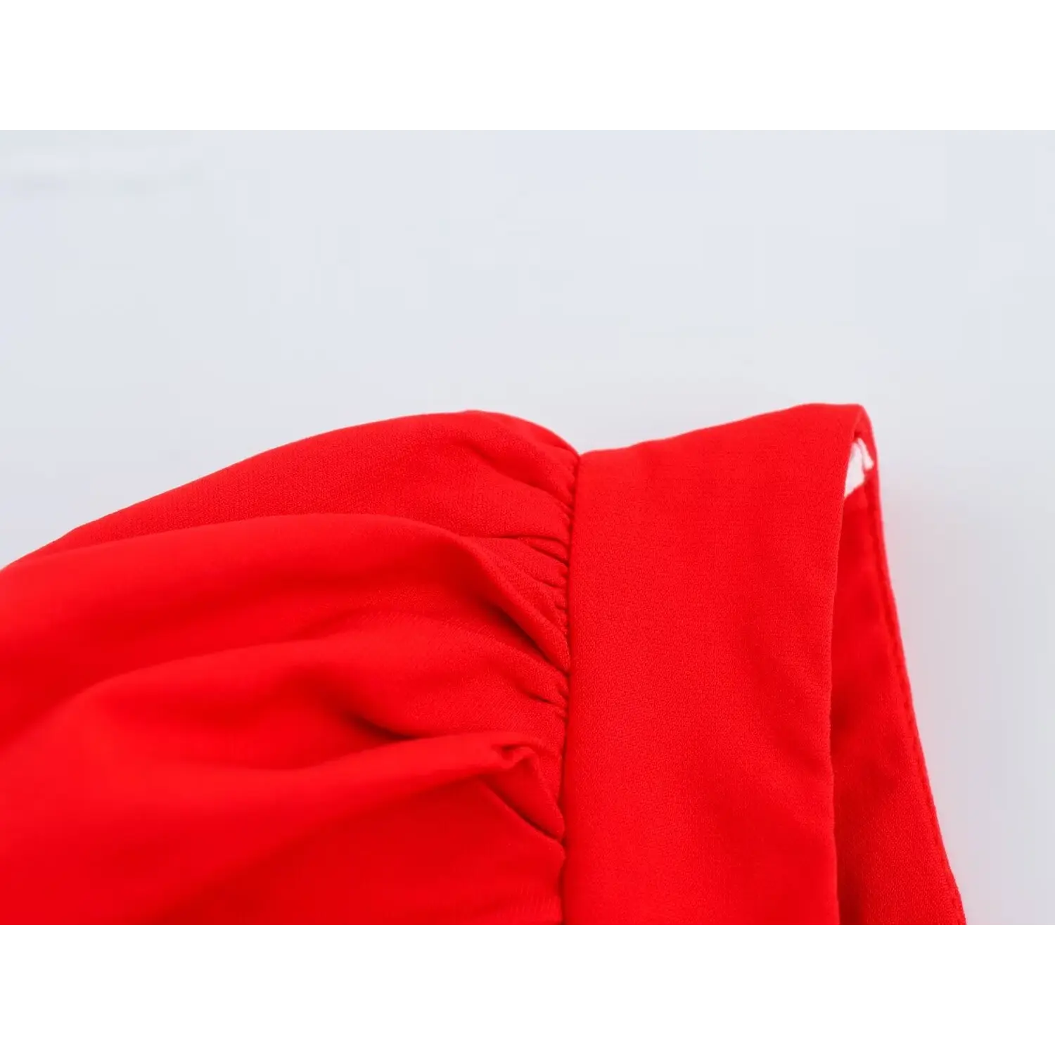 Close-up of puff sleeve gathering detail on bright red square neck corset top