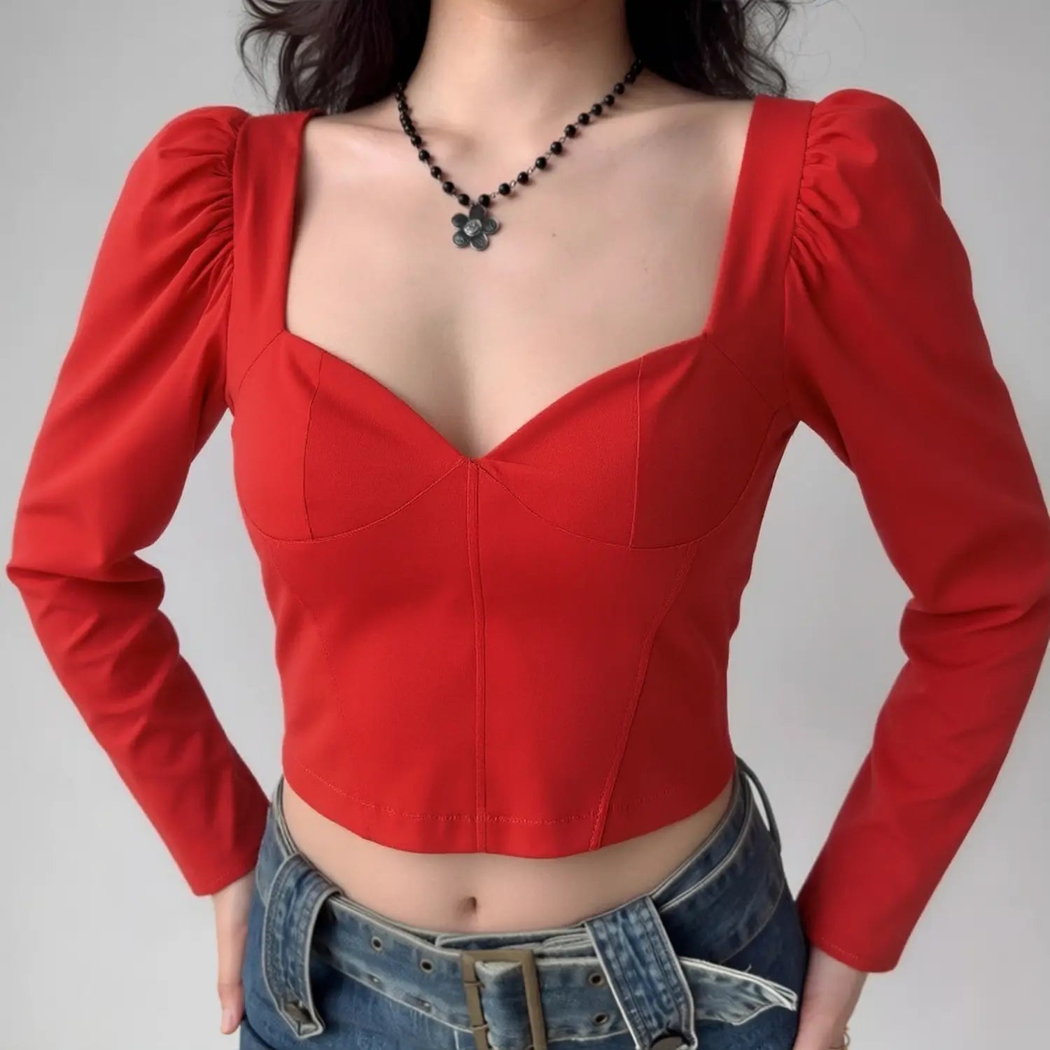 Lifestyle wearing shot of bright red puff sleeve corset crop top with sweetheart neckline, paired with denim jeans