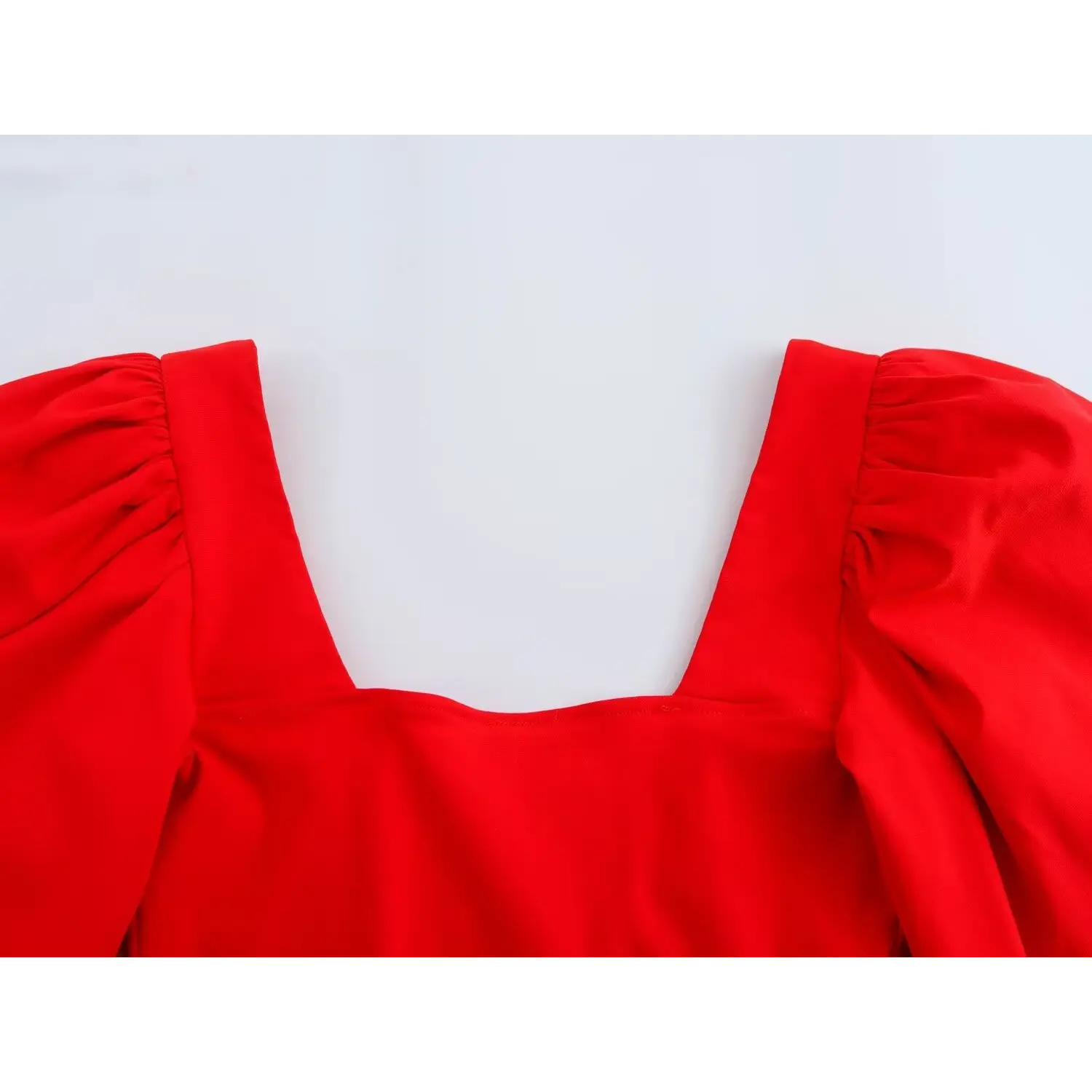 Close-up of square neckline and puff shoulder detail on bright red woven corset crop top
