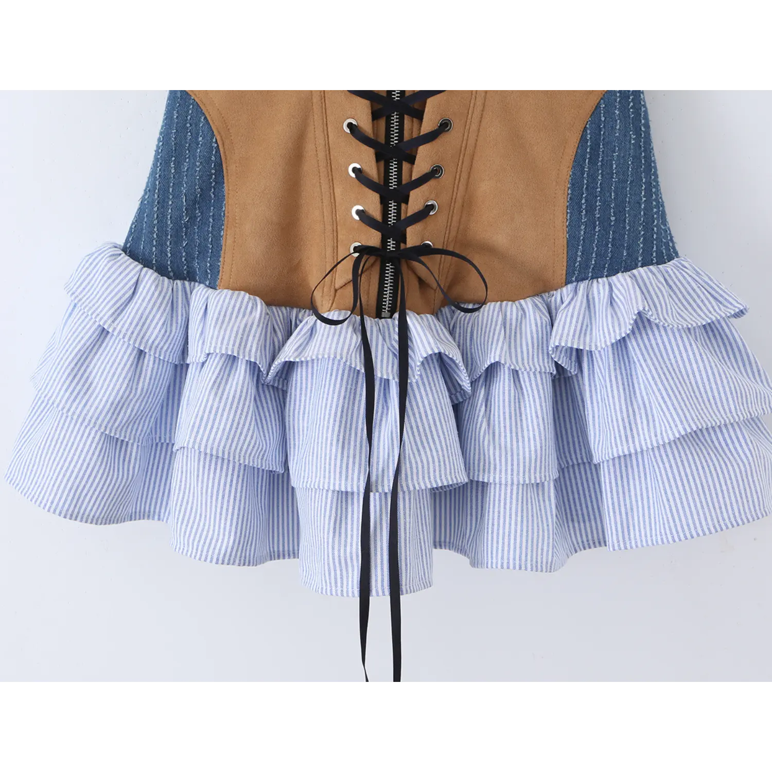 Close-up shot of the tiered ruffle hem of a halter dress with suede, denim, and striped fabric details
