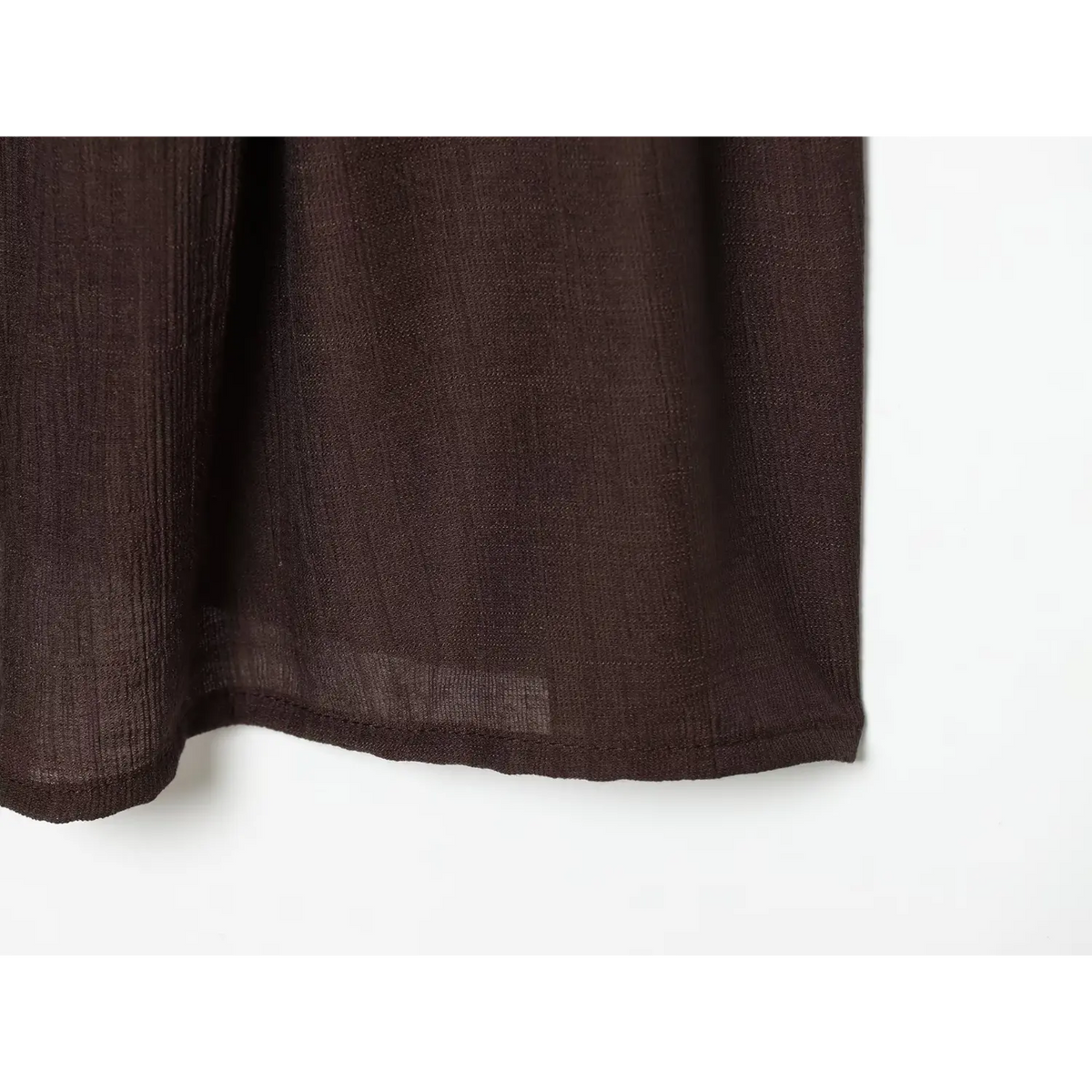 Close‑up crinkle textured woven fabric and finished hem edge of brown cami mini dress