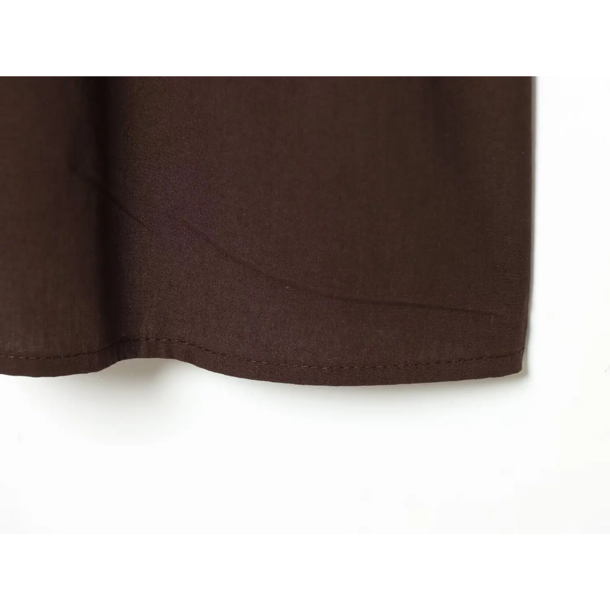 Close-up of finished hem and woven fabric texture of brown embroidered mini dress