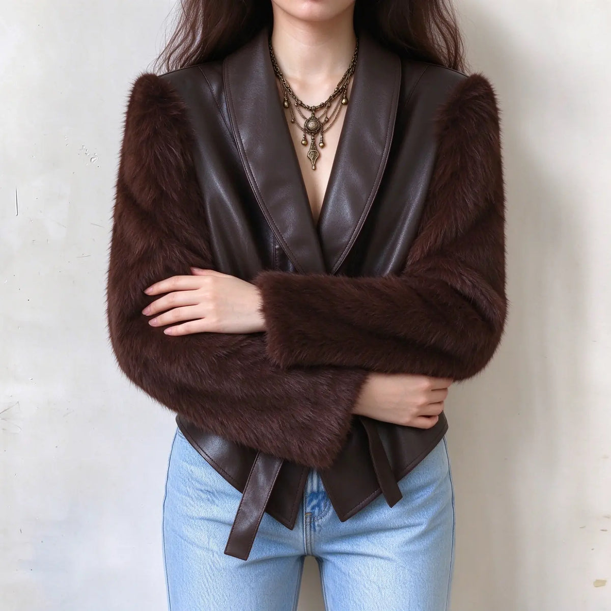 Female model in brown leather mix faux fur sleeve cropped jacket, wrapped arms pose, tied waist sash, vintage chic outerwear display