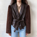 Female model wears brown faux leather jacket with fuzzy faux fur long sleeves, shawl lapel, self tie waist belt, front full torso shot