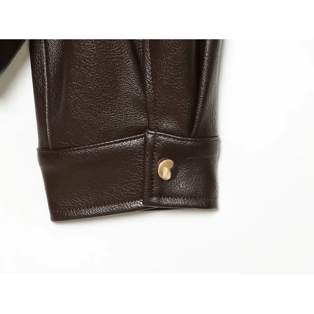 Close-up of gold button on leather cuff