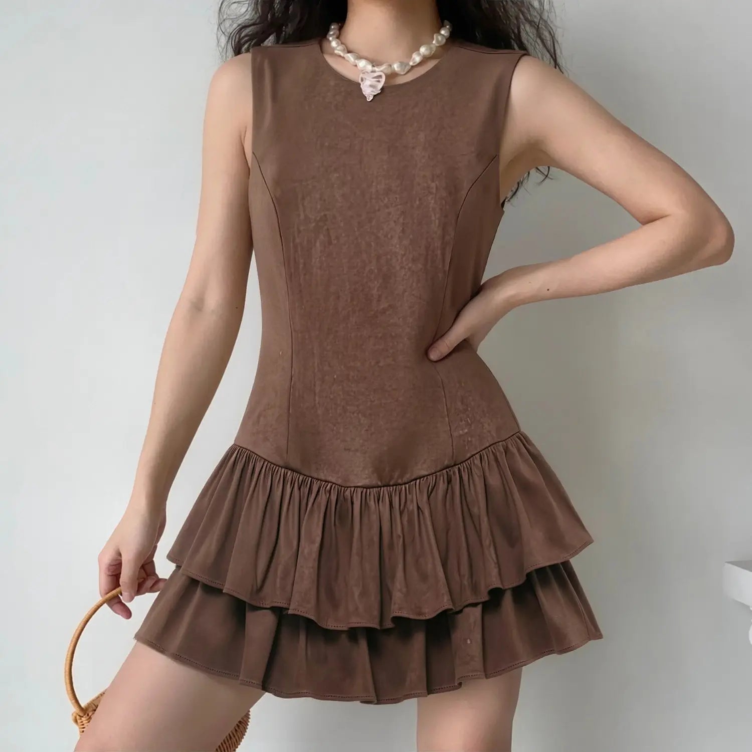 Model lifestyle shot wearing brown sleeveless faux suede mini dress with double ruffle hem