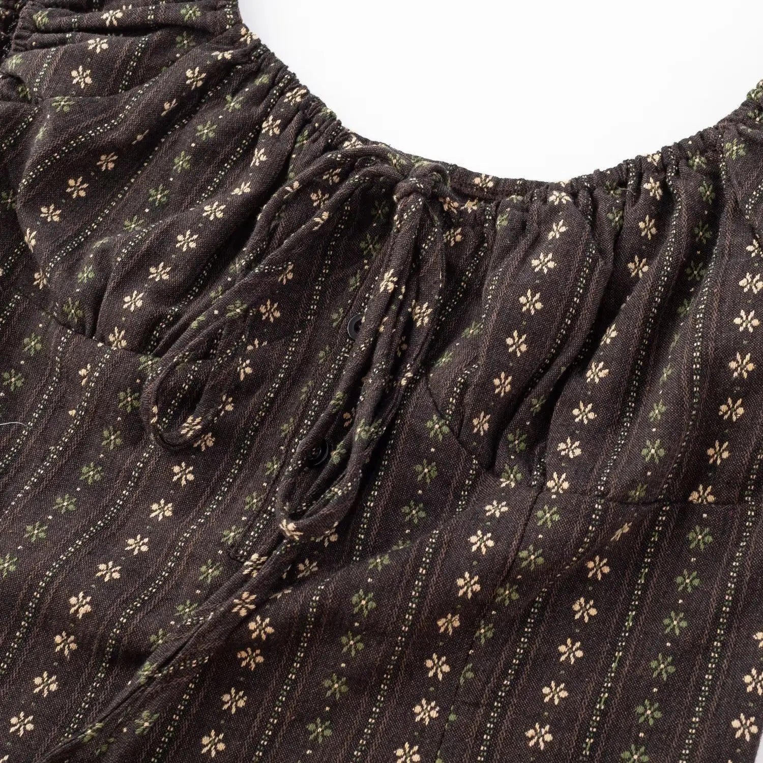 Dark brown vertical floral crop top front tie close-up, gathered ruched woven fabric flat lay detail on white background