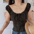 Dark brown floral ruched cap sleeve crop top, adjustable front tie fitted cut, partial indoor model shot with straw hat beside body