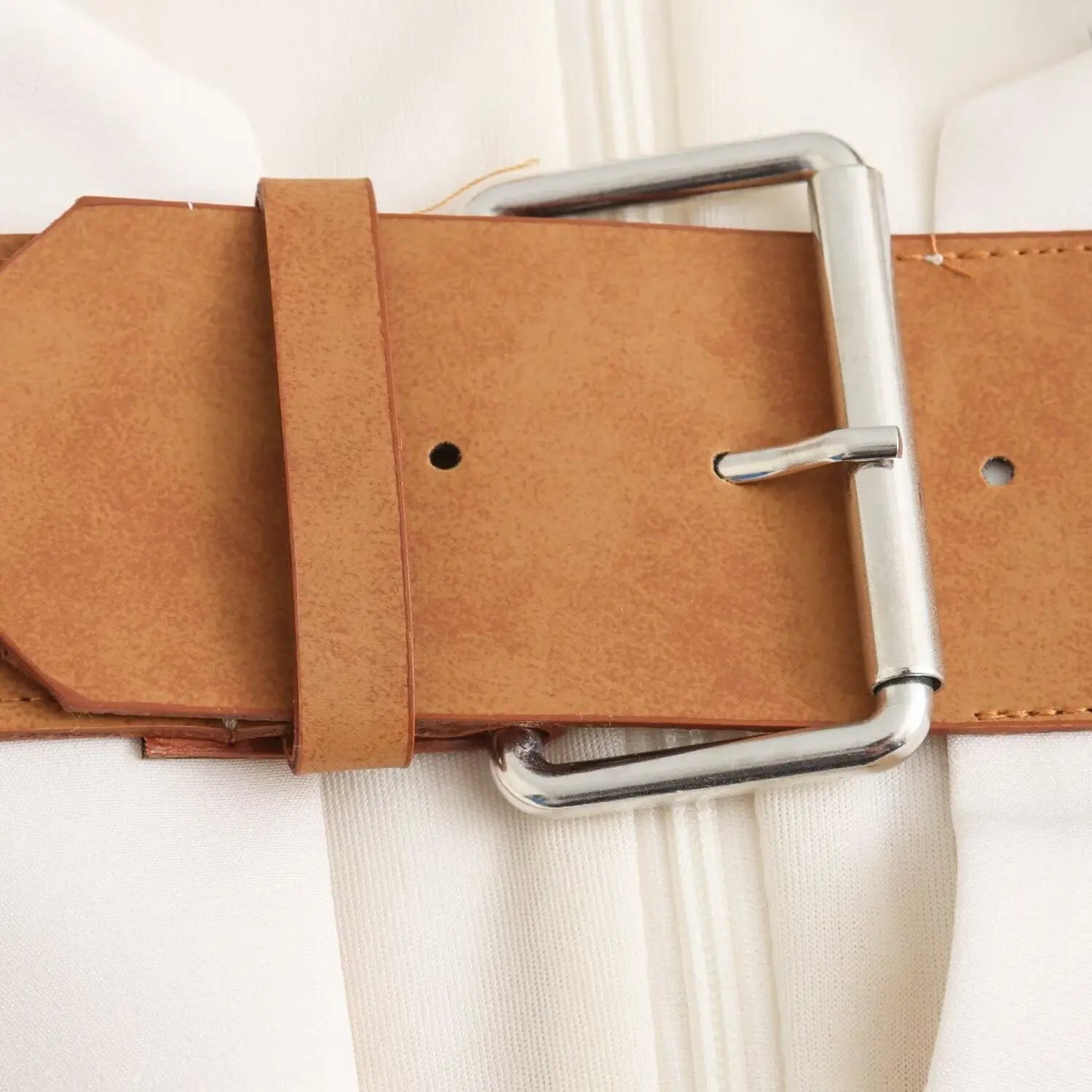 Macro close‑up of silver metal prong buckle, faux leather belt eyelets and stitching detail