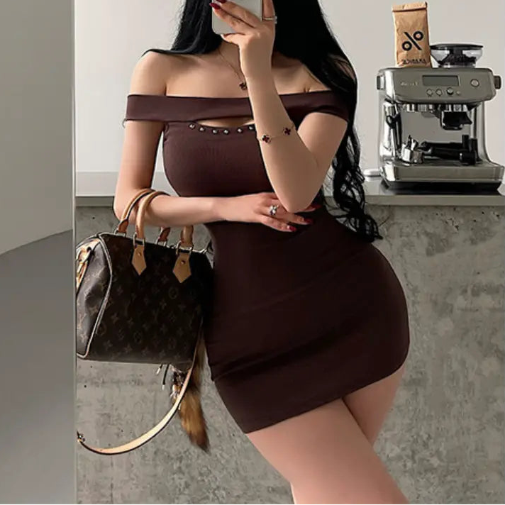 A woman taking a mirror selfie while wearing a brown ribbed off-shoulder mini dress with stud details, styled with a Louis Vuitton bag.