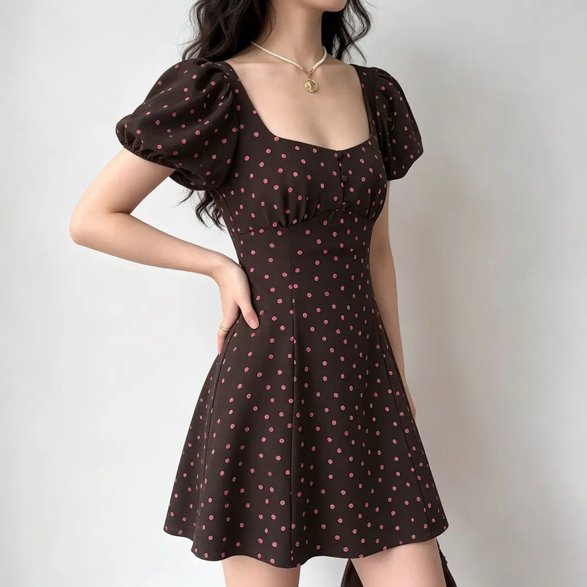 Side view of a brown and pink polka dot puff-sleeve mini dress, showcasing the fitted bodice, puff sleeves, and flared A-line skirt.