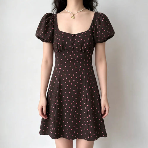 Model wearing a brown and pink polka dot mini dress with a square neckline, puff sleeves, and a buttoned bodice.