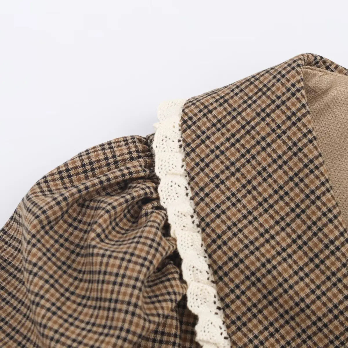 Close-up of the white lace trim on the sailor collar and the gathered puff sleeve on a brown plaid dress.