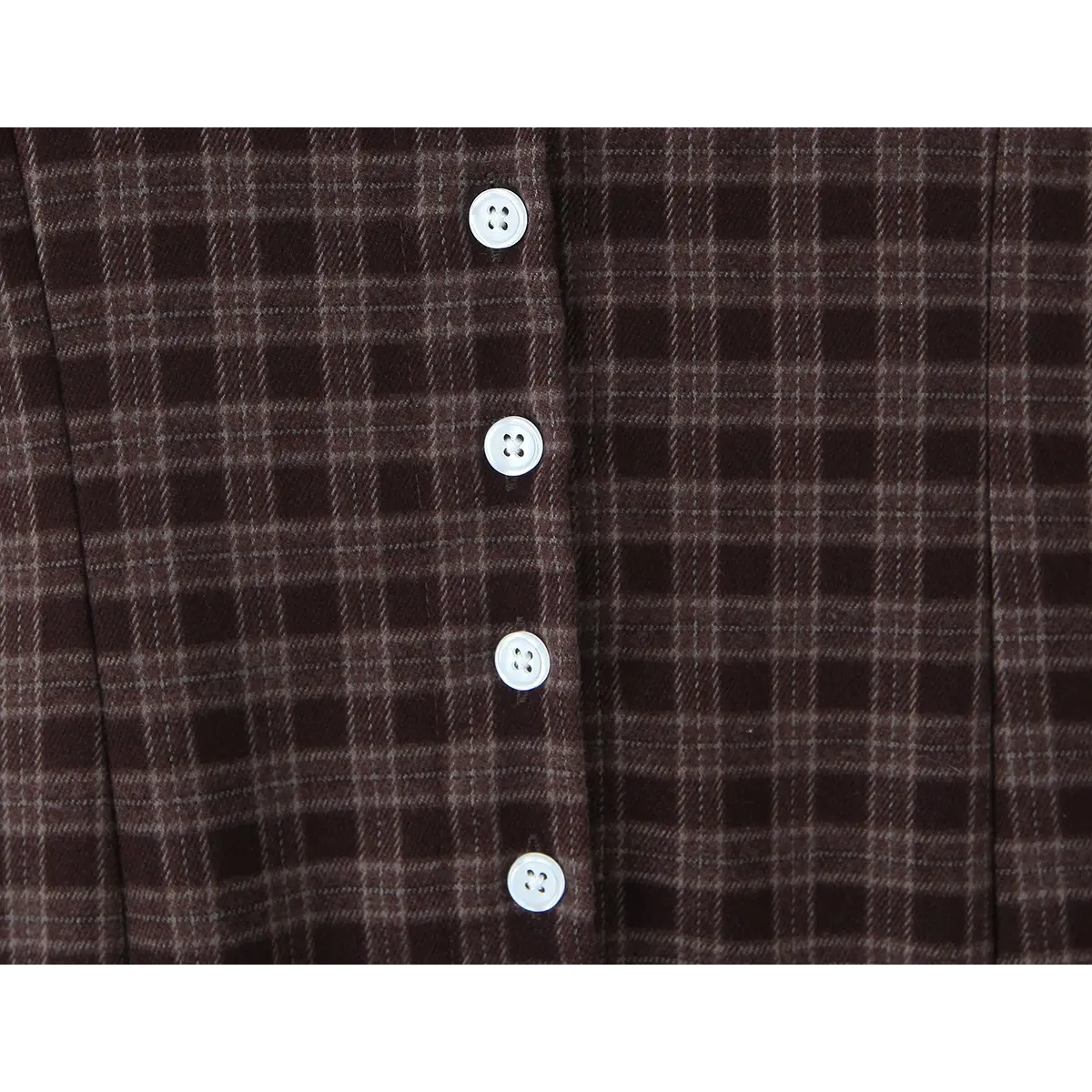 Close-up of the white front buttons, showing their alignment with the plaid pattern.