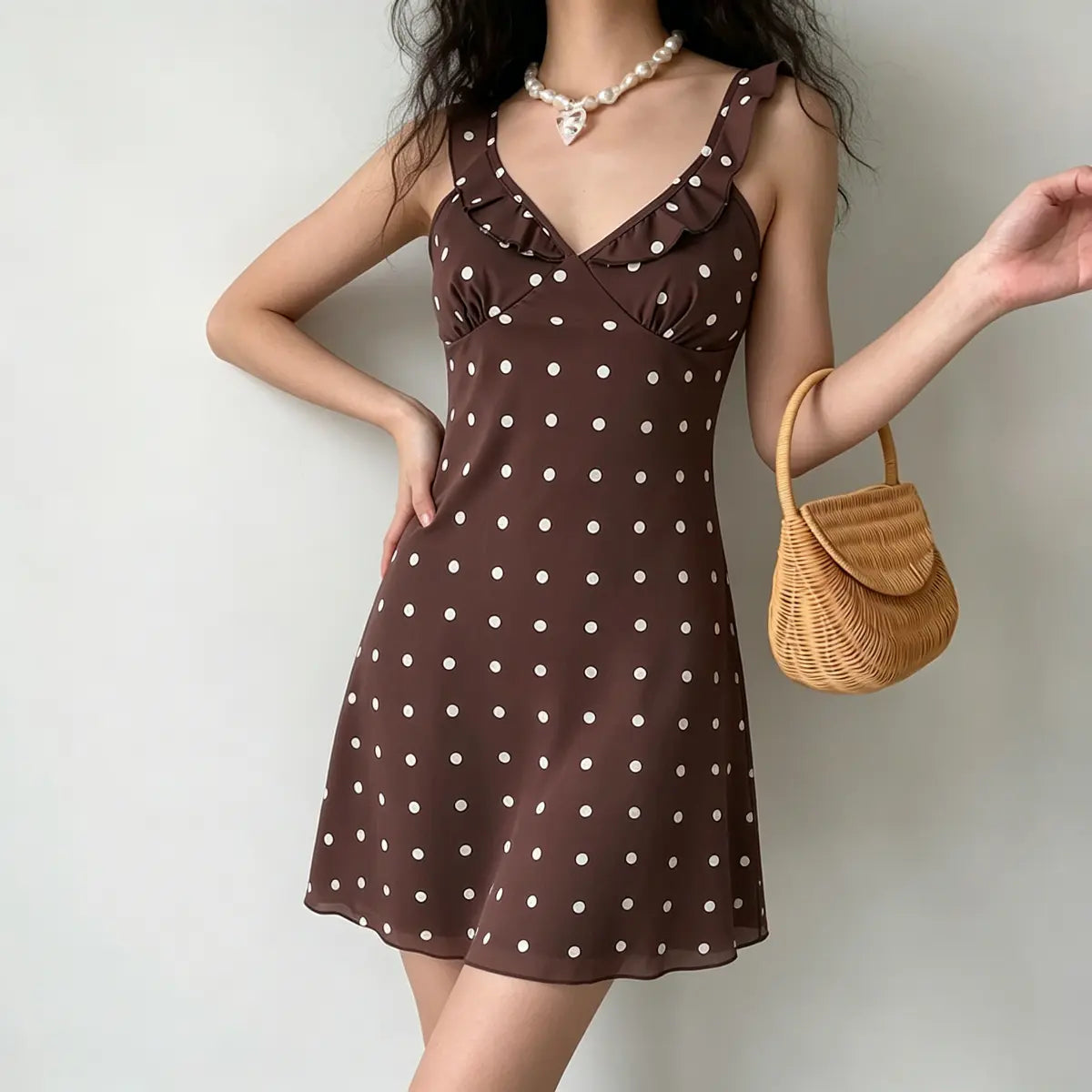 Full front view of model in brown polka dot mini dress, highlighting the ruffled neckline and fitted waist.