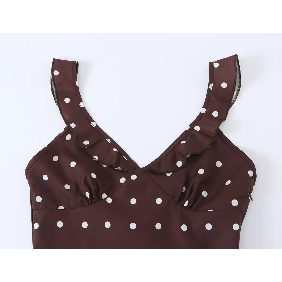 Close-up of the V-neckline and ruffled straps on brown polka dot dress, with subtle side zipper detail visible.