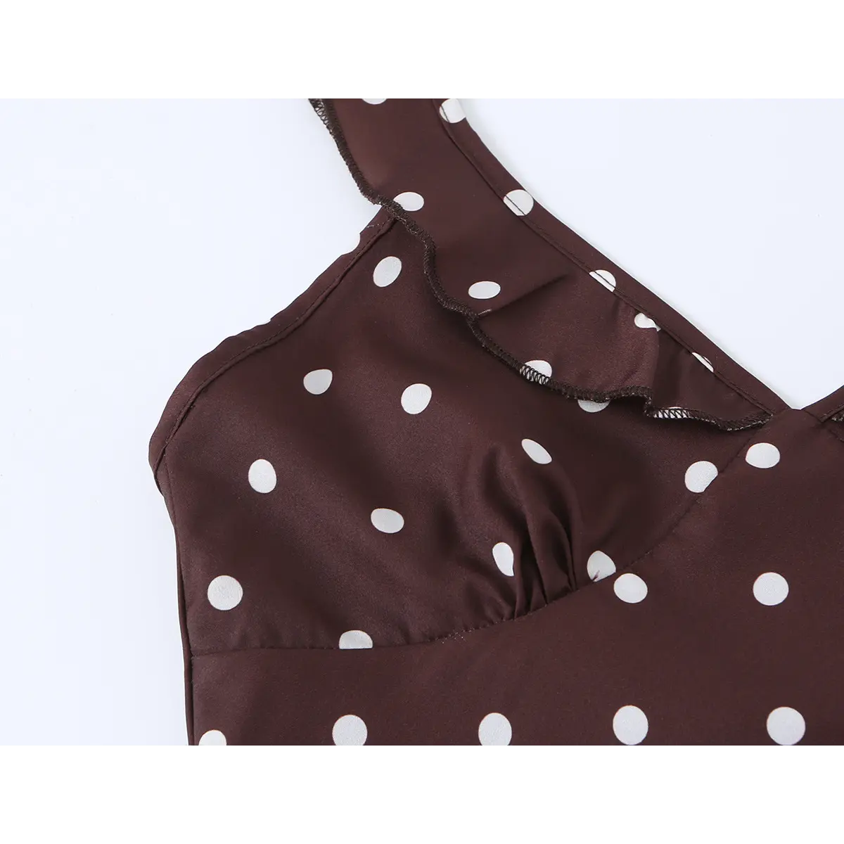 Detailed shot of the ruffled V-neckline and strap on brown polka dot dress, showing soft fabric texture.