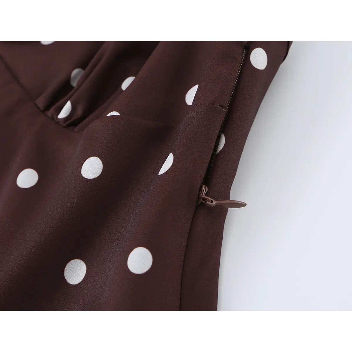 Close-up of the side zipper on brown polka dot dress, showing smooth closure and neat seam finish.